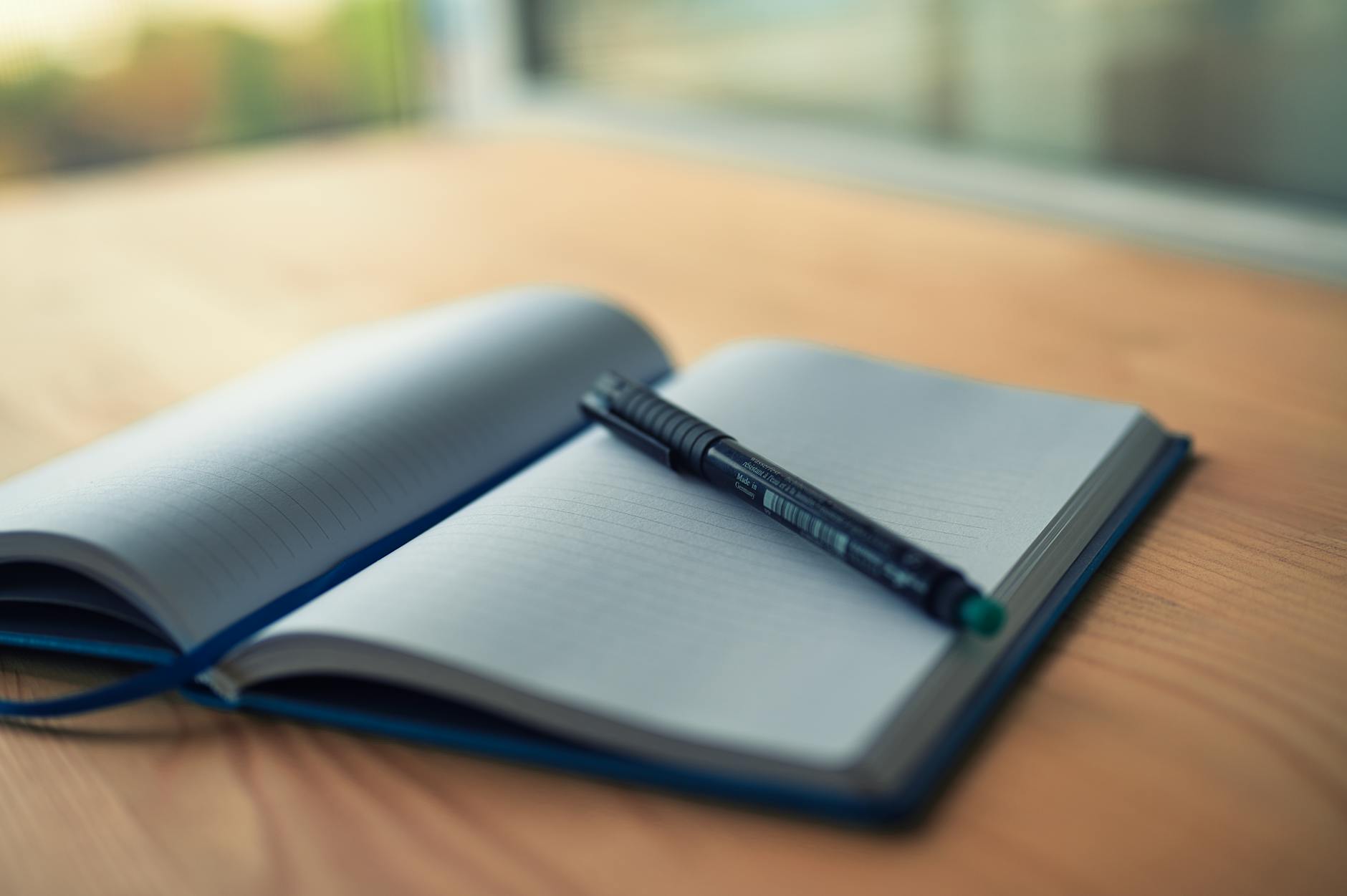 open notebook with pen on wooden desk